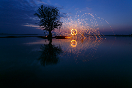 Reflection of swing fire on waterの写真素材