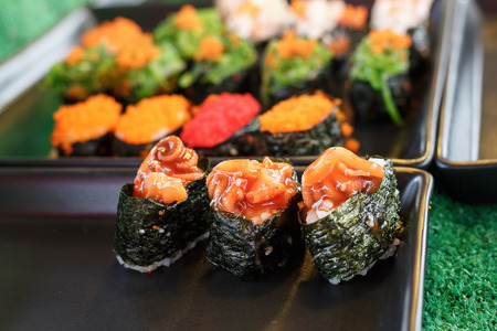 Sushi and sushi rolls served on black  tray at the market, variousの写真素材
