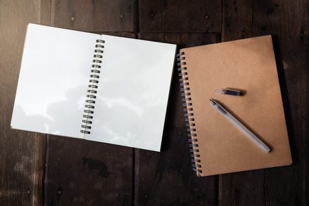 Pen and recycle notebook on wood background with flareの写真素材