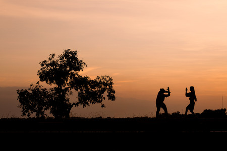 Silhouette man and woman with beautiful the sky at sunset.
Background, he and she inside sweetheart, They were both playing and happy.の写真素材