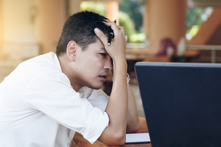 The Businessman working outside the office, with laptop, pen, and he stressed. He must fix. And He was thinkingの写真素材