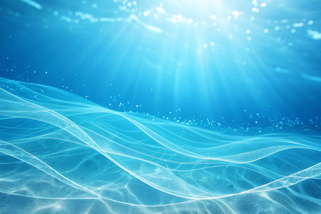 This is an abstract underwater shot showcasing the mesmerizing patterns of sand ripples with sunbeams filtering through the clear blue water, creating a serene and ethereal ambiance. Ideal for commercial projects needing a calming, aquatic, or natural theme.の素材