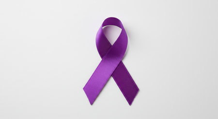 A neatly folded purple ribbon sits isolated on a plain white surface, promoting awareness for various causes like pancreatic cancer, lupus, or domestic violence. The clean and simple composition makes it versatile for campaigns and informational materials.の素材