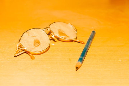 Old glasses and pencil filled with dust on the tableの写真素材