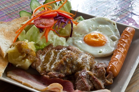 Steak pork, bacon, fried egg, sausage, bread and salad.の写真素材