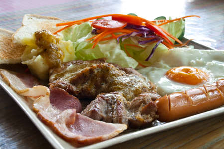 Steak pork, bacon, fried egg, sausage, bread and salad.の写真素材