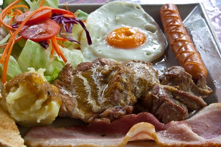 Steak pork, bacon, fried egg, sausage, bread and salad の写真素材