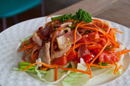 Spicy bacon salad with tomato carrot on white dish の写真素材