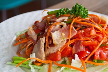 Spicy bacon salad with tomato carrot on white dish の写真素材
