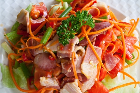 Spicy bacon salad with tomato carrot on white dish の写真素材