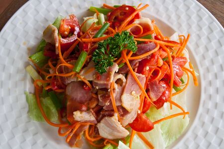 Spicy bacon salad with tomato carrot on white dish の写真素材