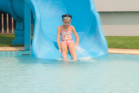 Girl play slider in the swimming pool in the daylight.の写真素材