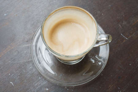Hot coffee latte in glass on a wooden brown.の写真素材