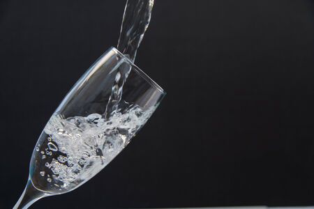 Pour water into the glass on a black background.の写真素材