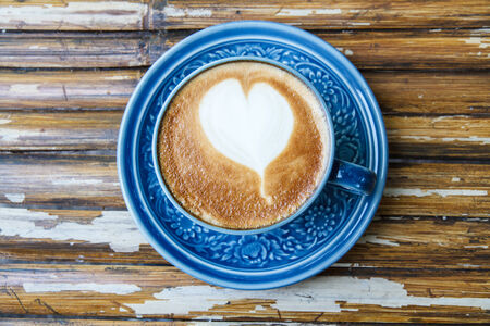 Hot coffee drawing hearts in blue glass.の写真素材