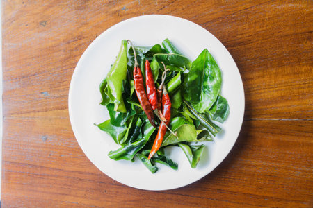 Fried chili and kaffir lime leaves on white plate.