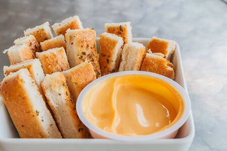 Breadsticks in white cup and brown sauce.の写真素材