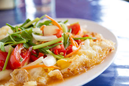 Spicy fried egg salad on white plate.の写真素材