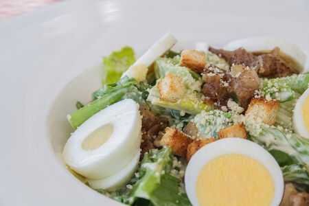 Caesar salad on white dish in restaurantの写真素材