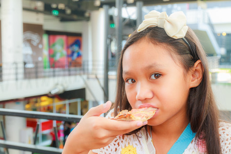 Asian girl child eat pizza in a restaurantの写真素材