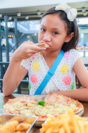 Asian girl child eat pizza in a restaurantの写真素材