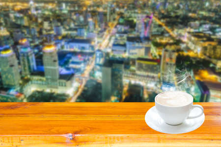 Concept: Coffee on wood table backdrop Cityscape night.の写真素材