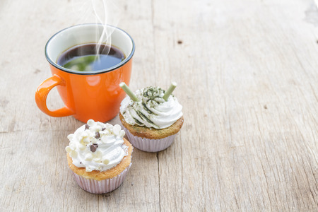 Coffee cup of orange and Cupcake matcha green tea and chocolate put on the wood.の写真素材