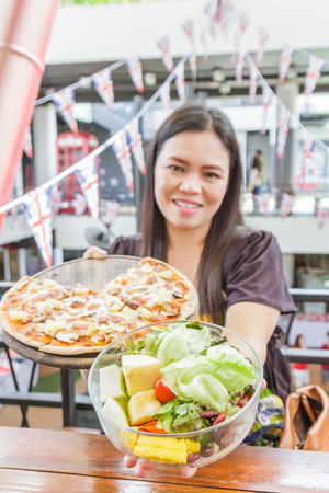 Asia girl choice food pizza or salad in restaurantの写真素材