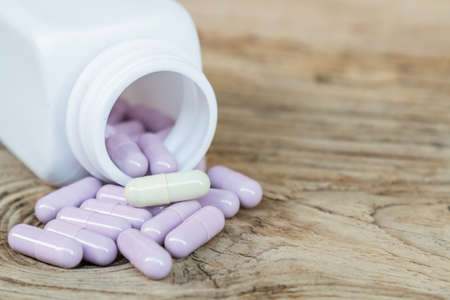 Bottle drug purple and yellow capsule on wood table.の写真素材