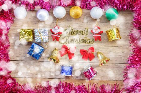 Xmas day: Snow Merry Christmas decoration with gift box, ball, bell, drum, bow, tassel and santa claus doll on wood background. Top view.の写真素材