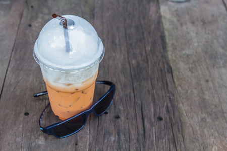 Iced milk tea and sunglass on wood table.の写真素材