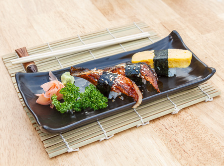 Japanese Food Unagi Sushi and Sweet egg Sushi in black plate on wooden table.の写真素材