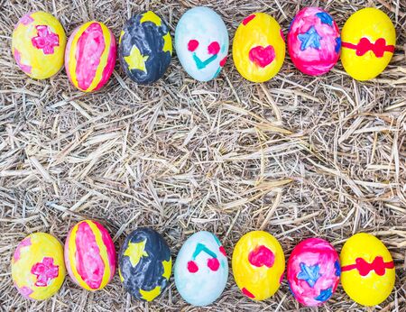 Easter eggs color black, red, yellow and blue coloring Heart, Bow, star and Red Cross emblem on straw. top view.の写真素材