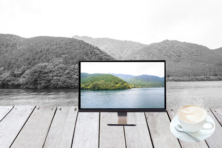 Monitor on plank wooden front show Lake Ashi, Tokyo, Japan and hot coffee.の写真素材