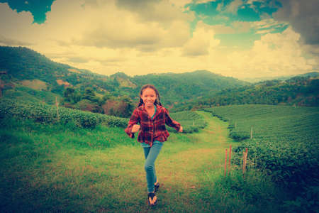 Asia girl run in Tea plantation on mountain at north Thailand with copy space. vintage style.の写真素材