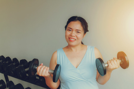 Asia fat woman training dumbbell in the gym for strength, weight loss.の写真素材