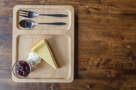 Blueberry cheesecake with cream and spoon and fork on wood plate at restaurant. top view.の写真素材