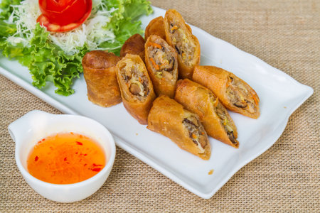 Deep fried spring rolls and sweet sauce on white plate.