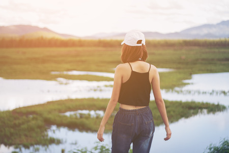 Asia girl relax in nature have mountain and water at background. Selective focus and soft flare sunlight.の写真素材