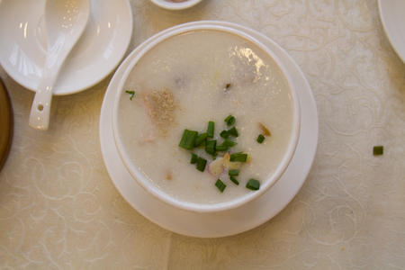 Congee or Rice porridge with coriander and spoon in a restaurant. top view.の写真素材