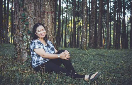 Asia woman relax sit on grass in wood forest with copy space.の写真素材