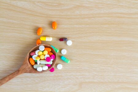 Medicine is pill and capsule on wood spoon with copy space on wood table. top view.の写真素材