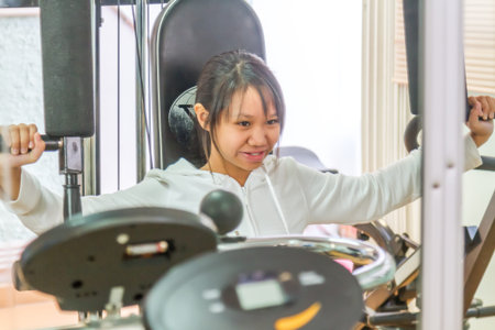 Asia teenage girl training arm equipment in the gym for strength.