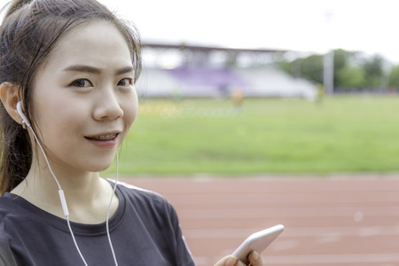 Asia girl listen music sear sportswear background public stadium with copy space.の写真素材