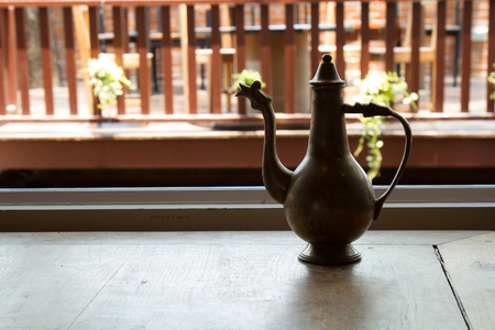 Teapot brass antique on wood table background sunlight with copy space.の写真素材