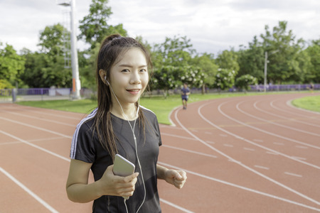 Asia girl listen music sear sportswear background public stadium with copy space.の写真素材