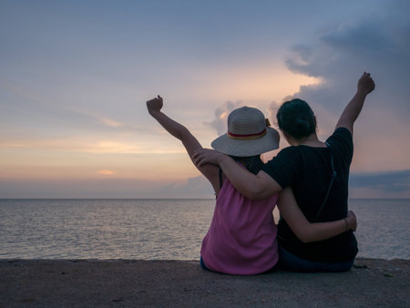 Asia mother and daughter are cheerful and background sunset at the sea with copy space.の写真素材