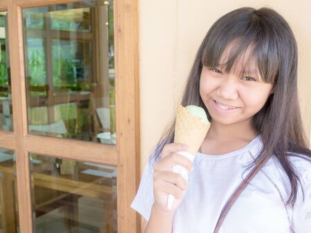 Asia teenage girl eat green tea ice cream cone at restaurantの写真素材