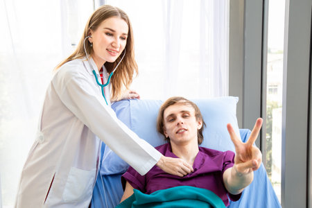 The female doctor is wearing a doctor uniform use the stethoscope to check the pulse of the male patient smiled and raised the excellent finger lying on the bed. Concept examination of the symptoms.の写真素材