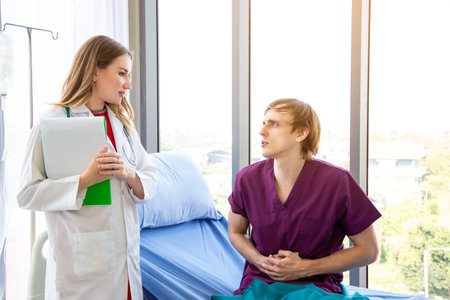 The female doctor is wearing a doctor uniform examining the symptoms of a patient is stomach ache patient sitting in bed. Concept examination of the symptoms of stomach ache.の写真素材